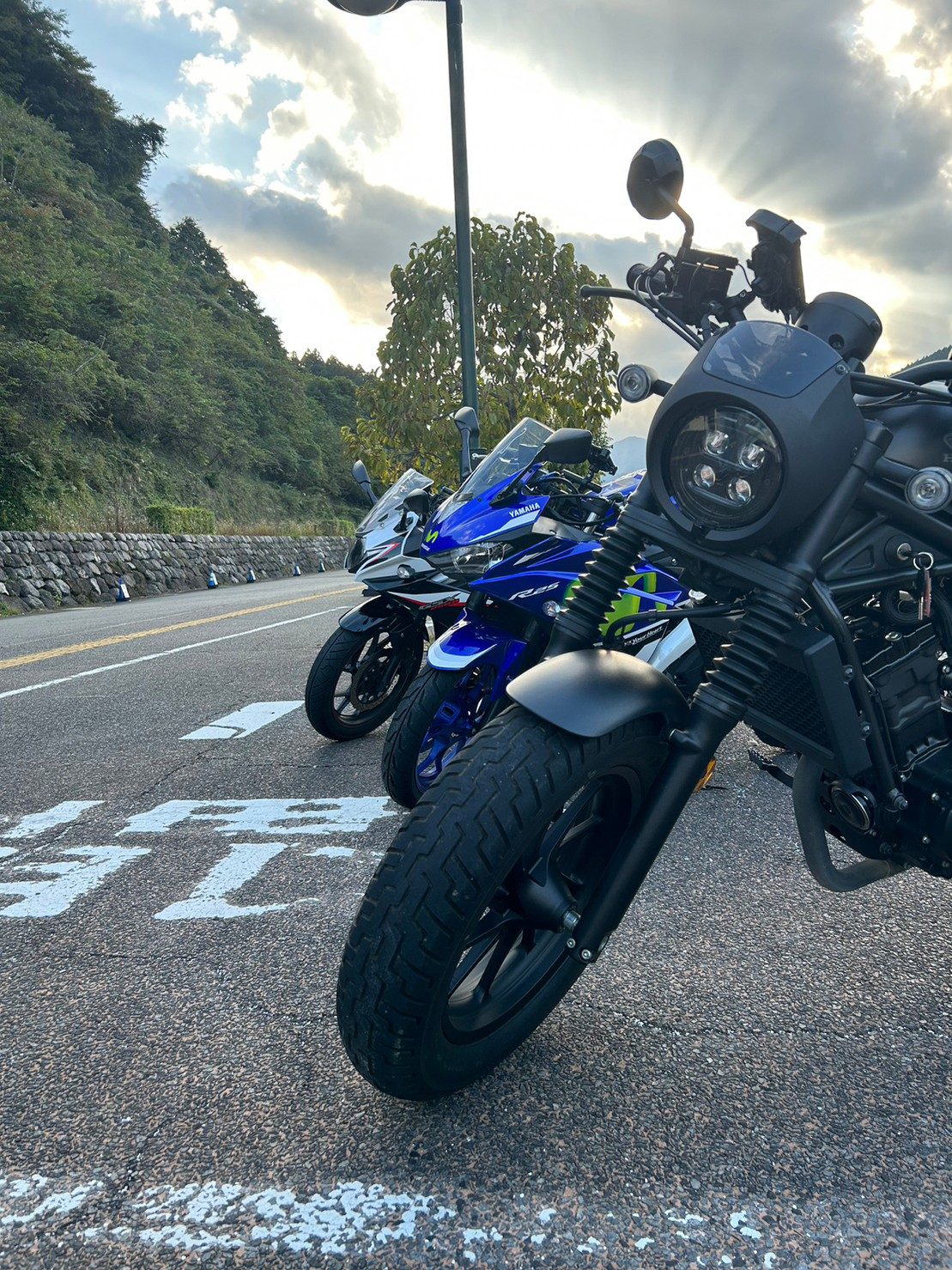 黒いネイキッドバイクを間近から。日没が近づき、雲間から強い陽光が差し込んでシルエットがはっきり出ていた